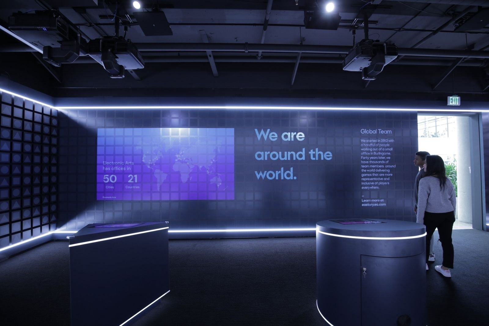 Electronic Arts: Dark exhibition room with screens and a world map