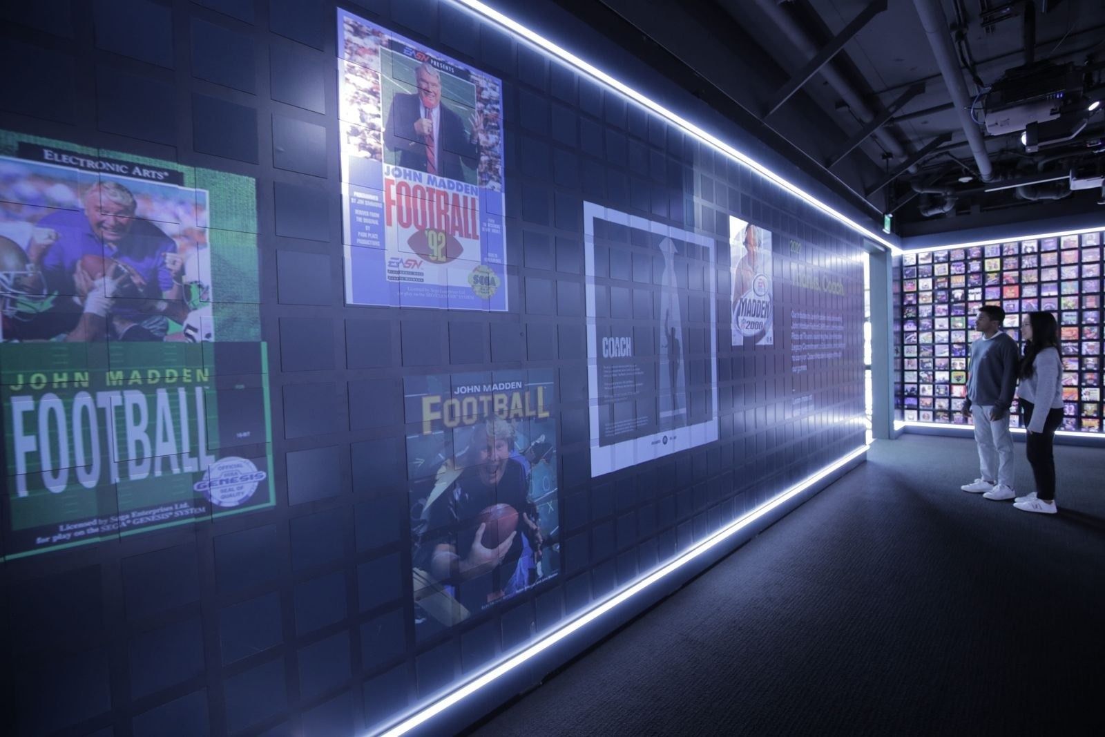 Electronic Arts: Game cover posters lit along a dark exhibit corridor