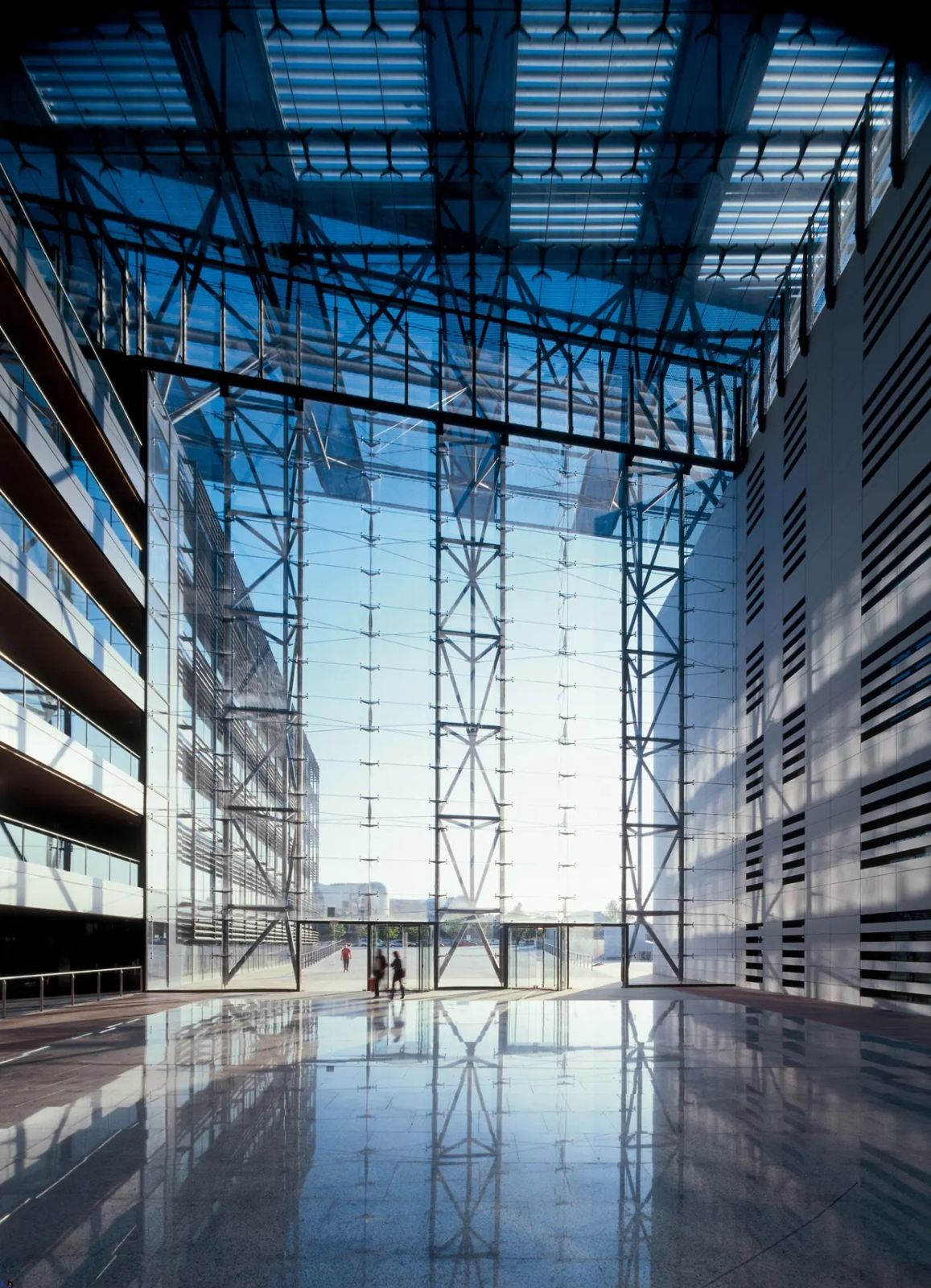 Endesa: A towering glass atrium wall with a reflective stone floor and a few people walking