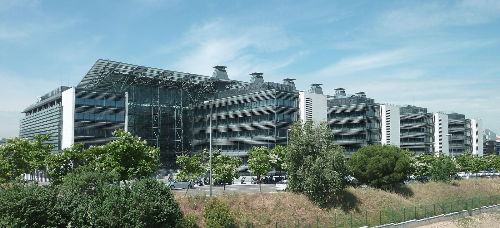 Endesa: Office wings with roof canopies seen behind trees and shrubs
