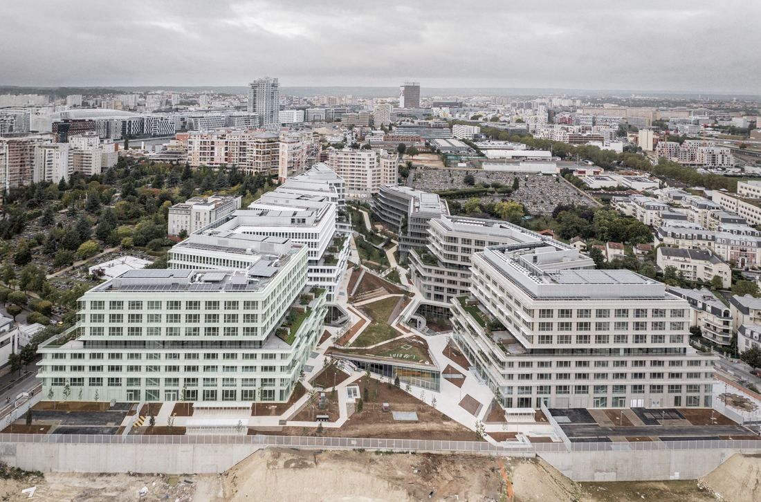 ENGIE: Aerial view of white office buildings arranged around green courtyards and terraces, with the city beyond
