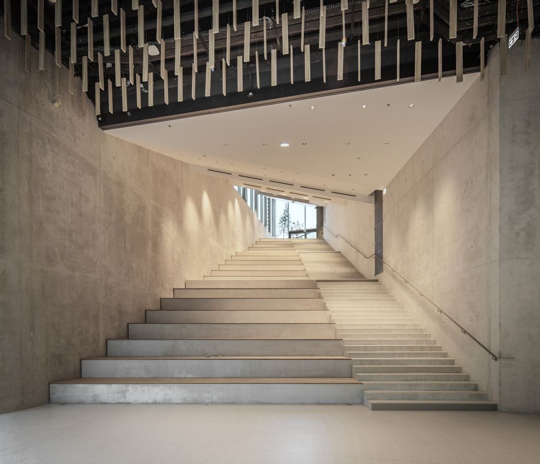 ENGIE: Broad concrete stepped stair rising beneath a timber batten ceiling