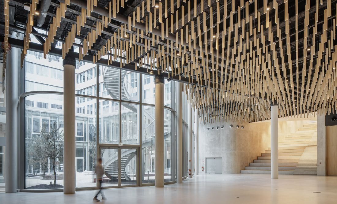 ENGIE: Tall glazed hall with a ceiling of hanging timber battens, wooden columns and a wide stair