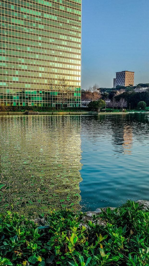 Eni: A glass facade reflected in still water at the lake's edge