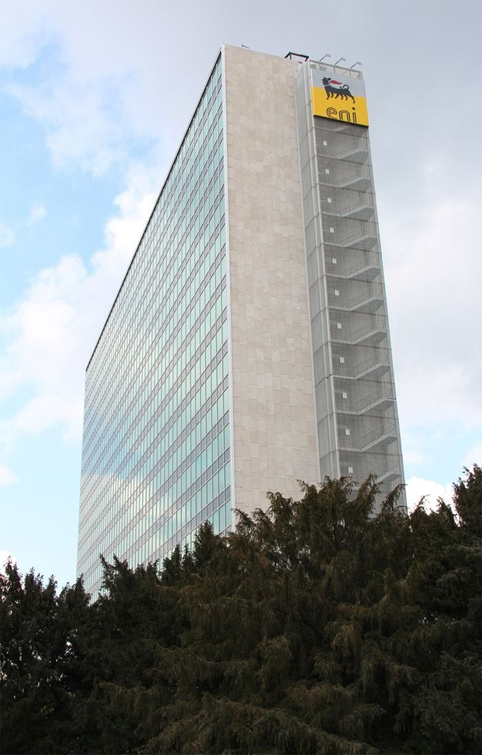 Eni: A narrow stone-clad end wall of a glass tower seen from below