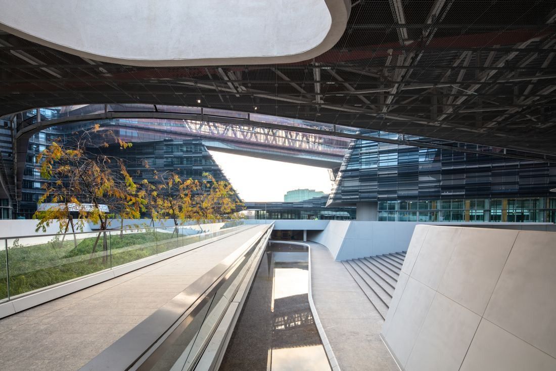 Eni: A sunken path with stairs beneath an overhanging canopy and office facades