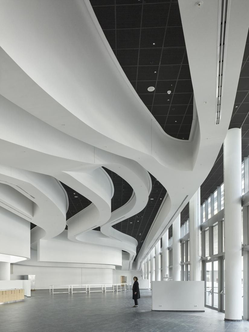 Eni: A white lobby with sweeping curved ceiling bands, tall glazing and slender columns
