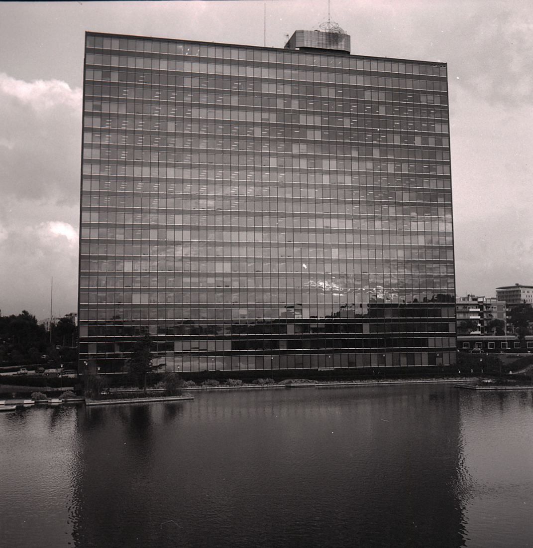 Eni: Black-and-white photo of a glass office slab above the water of a lake