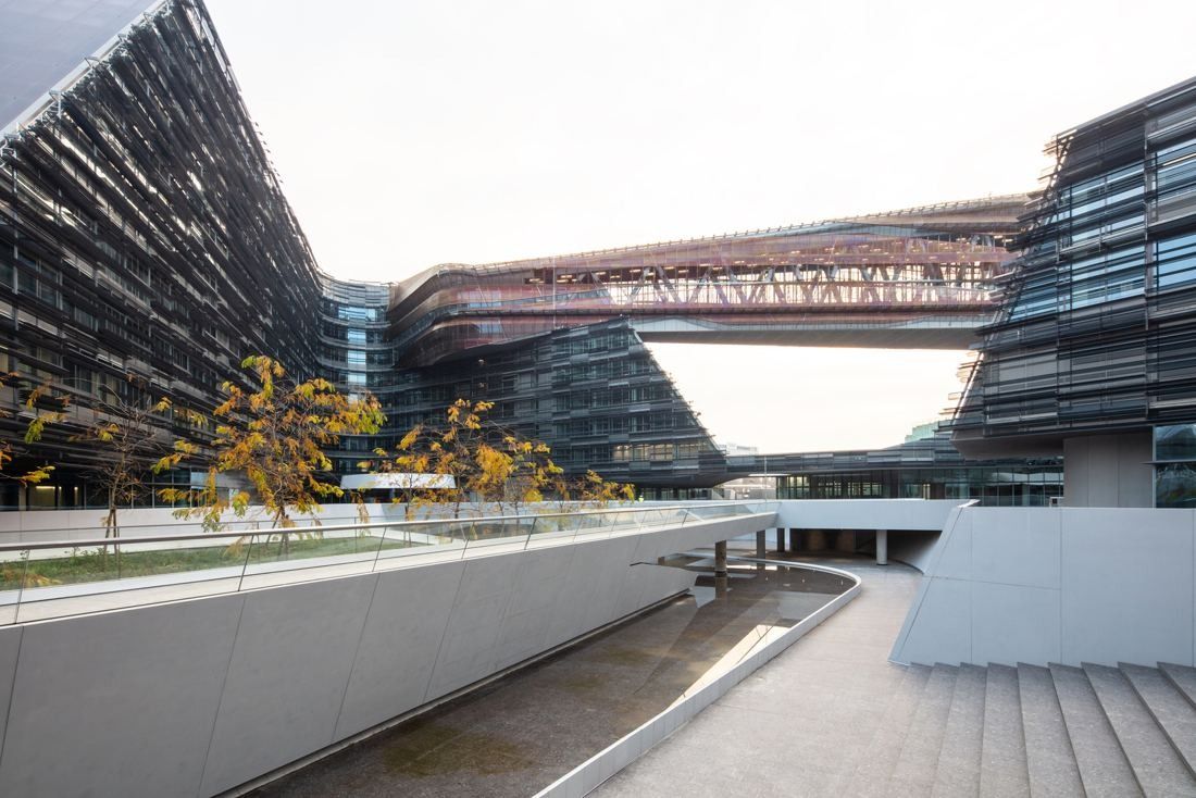 Eni: Stepped office blocks linked by a bridge above a sunken walkway and stairs