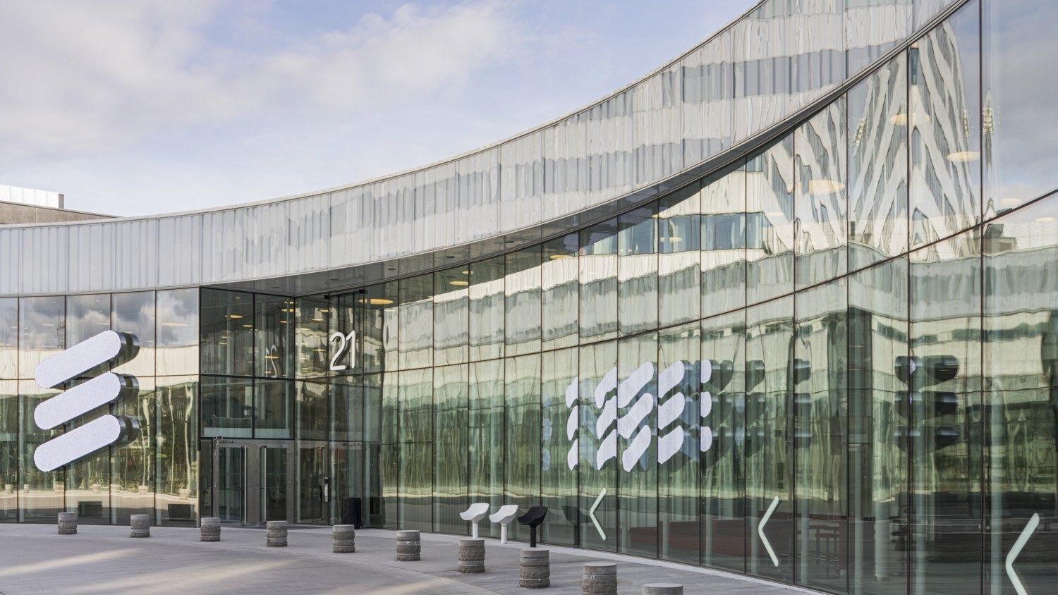 Ericsson: Curved glass entrance facade with large logo and the number 21