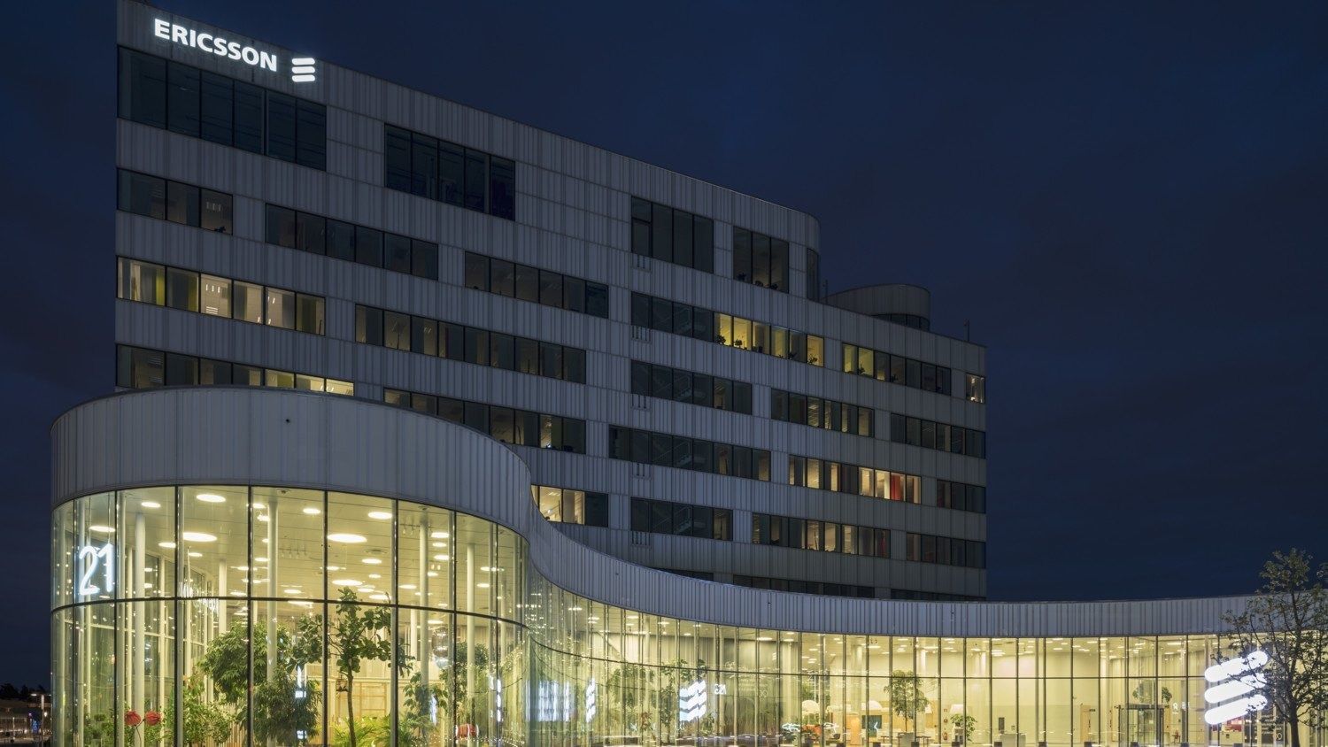 Ericsson: Office building at night with a glowing curved glass ground floor