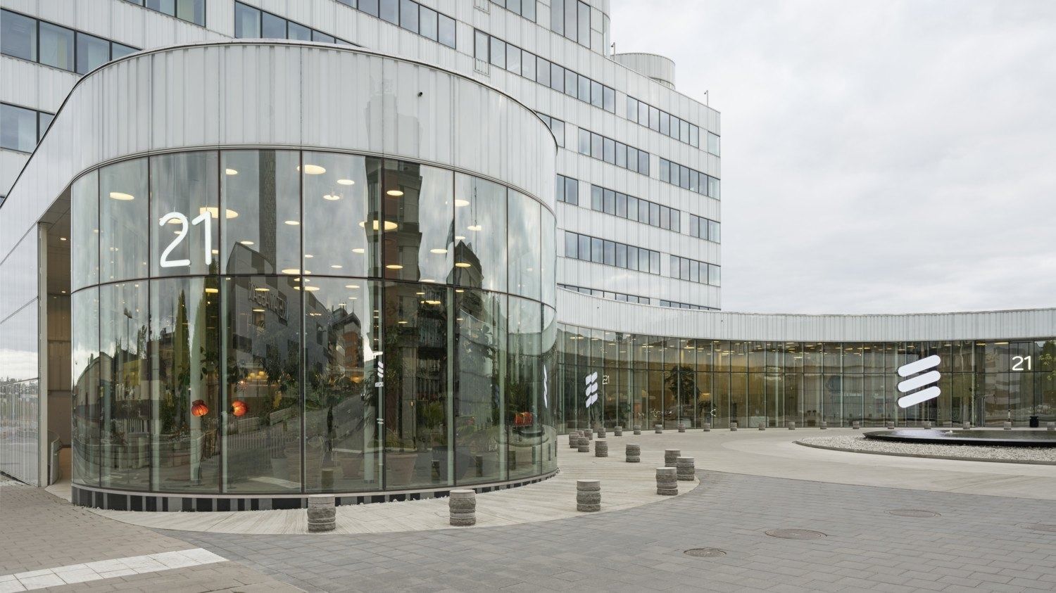 Ericsson: Round glass corner with the number 21, leading to a long curved glass facade