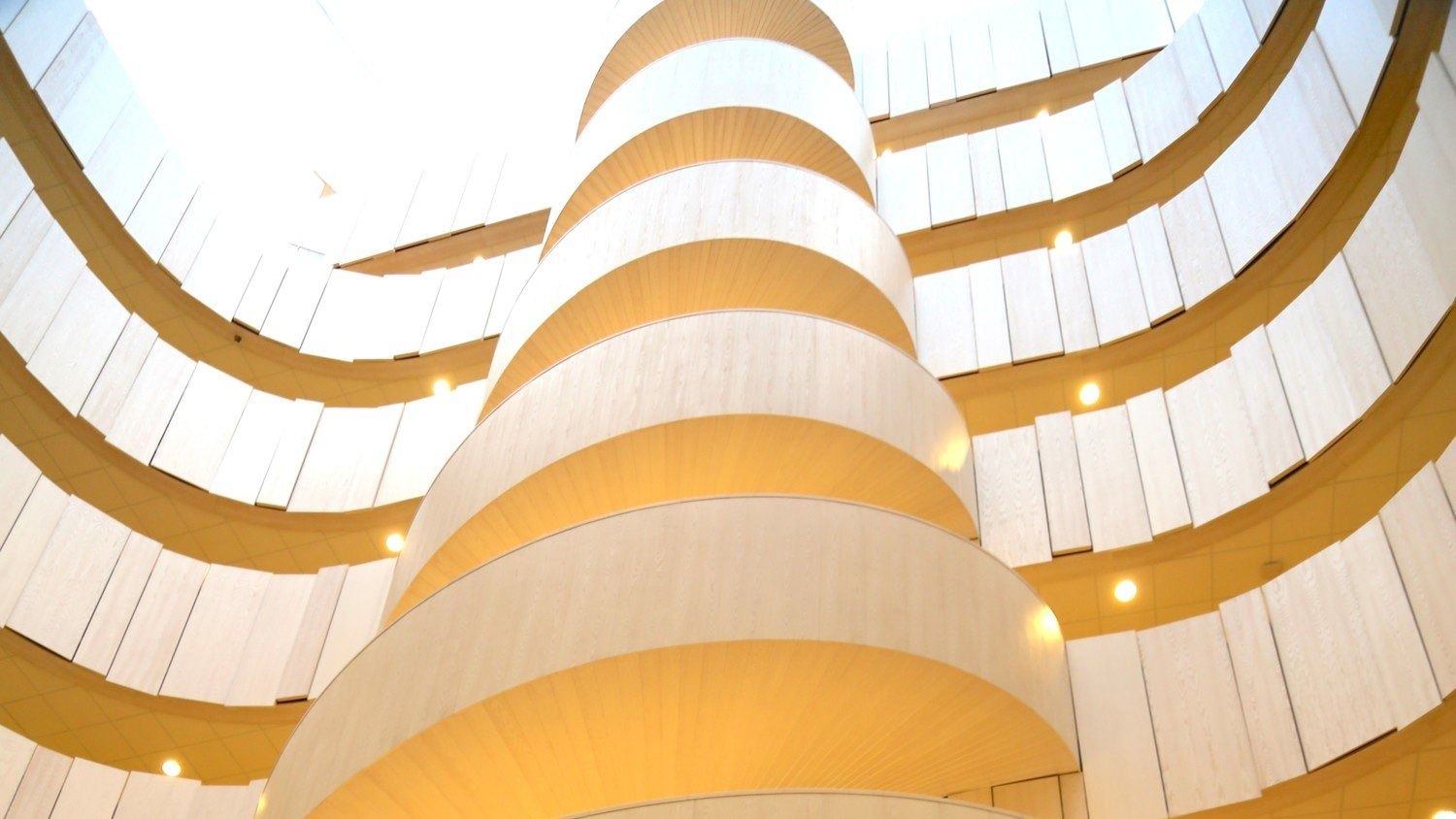 Ericsson: Spiral white balustrades of a round atrium lit in warm light