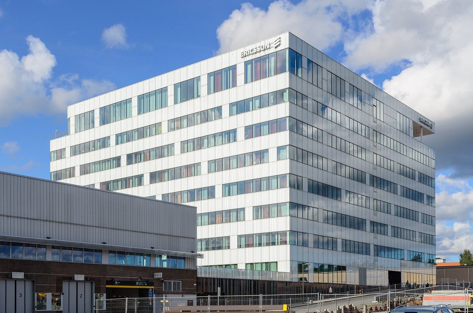 Ericsson: White multi-storey office building with horizontal window bands under a blue sky