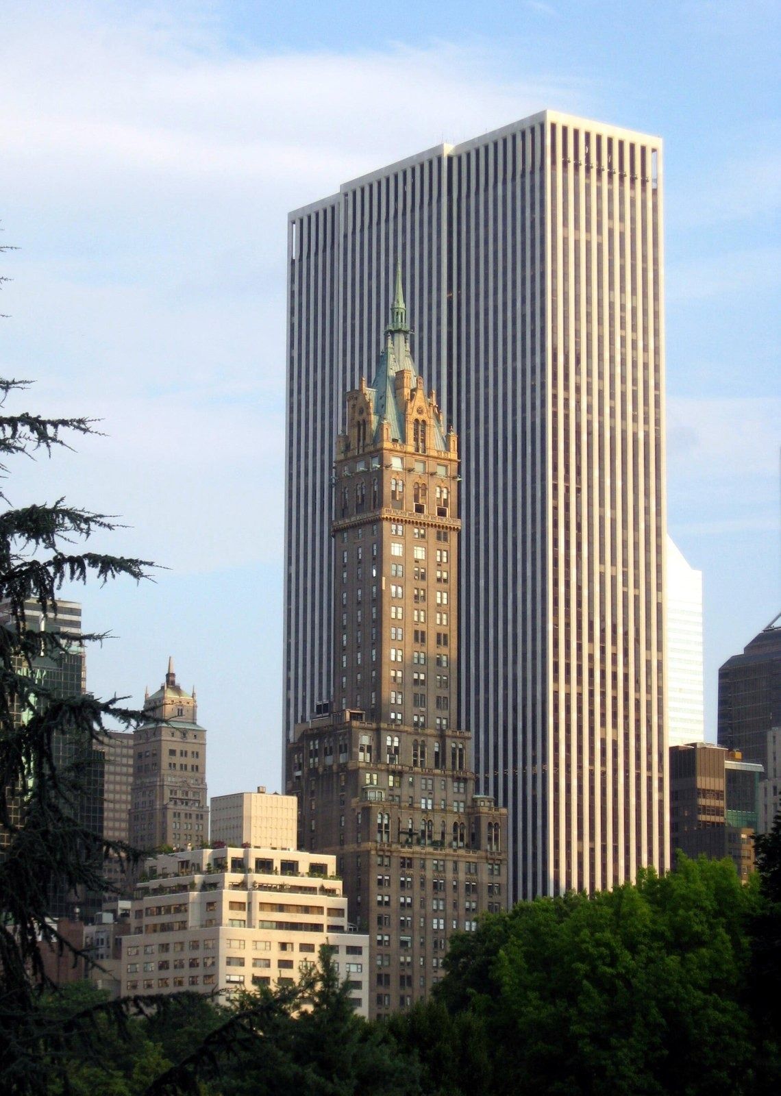 The Estée Lauder Companies: Striped skyscraper and ornate tower seen above trees from a park road