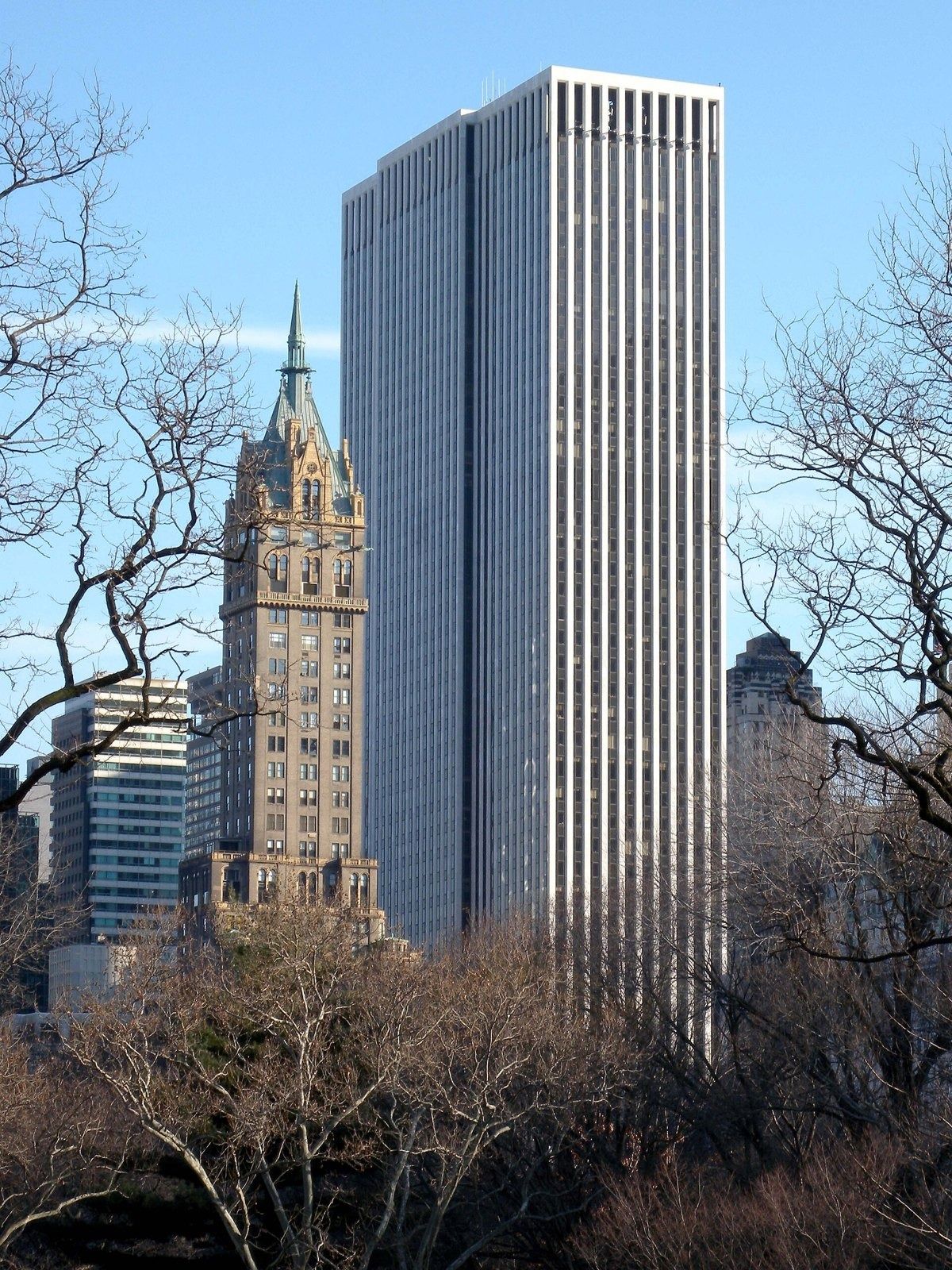 The Estée Lauder Companies: Striped skyscraper beside an ornate brown tower, seen past bare trees in a park