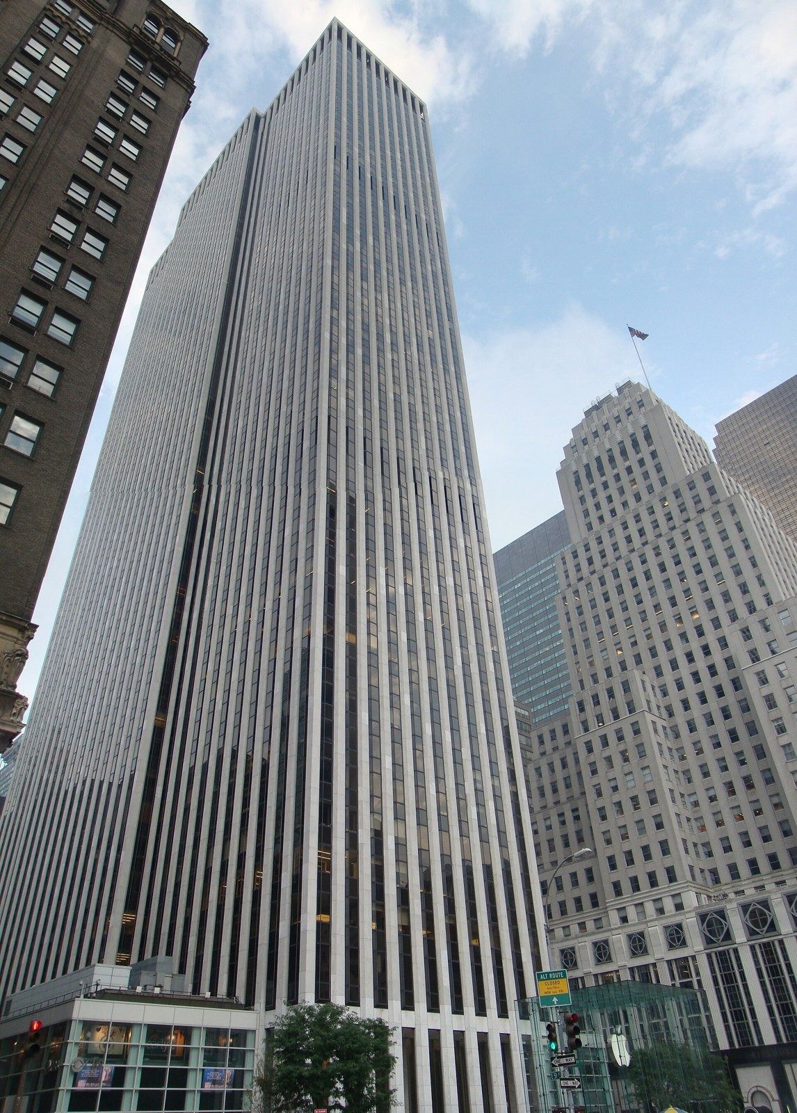 The Estée Lauder Companies: Tall white-striped tower beside older stepped skyscrapers, with a glass cube at street level