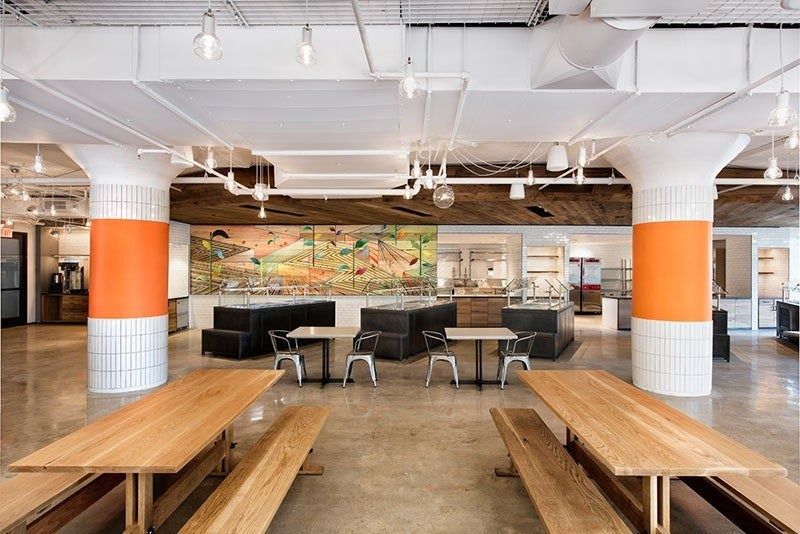 Etsy: Eatsy dining hall with long wooden tables and orange columns