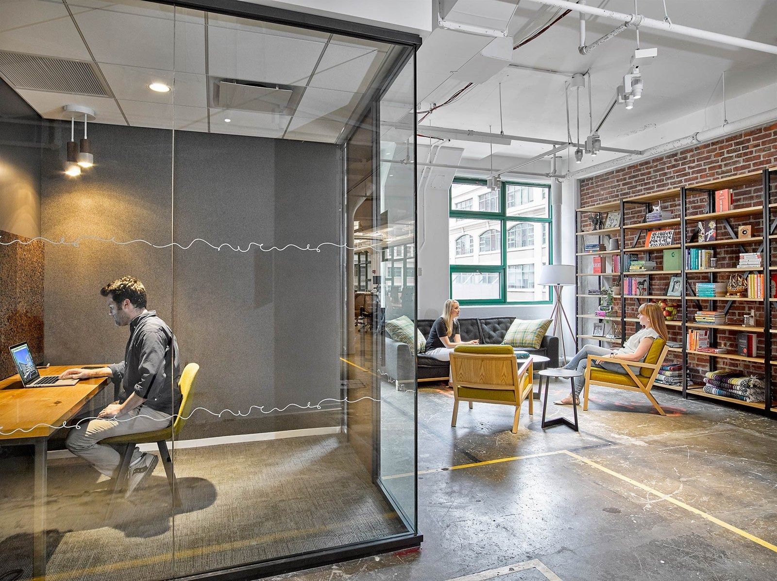 Etsy: Glass phone booth next to a library wall and lounge chairs