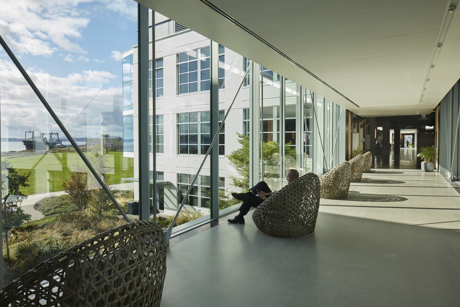 Expedia Group: Glass corridor with woven hanging chairs