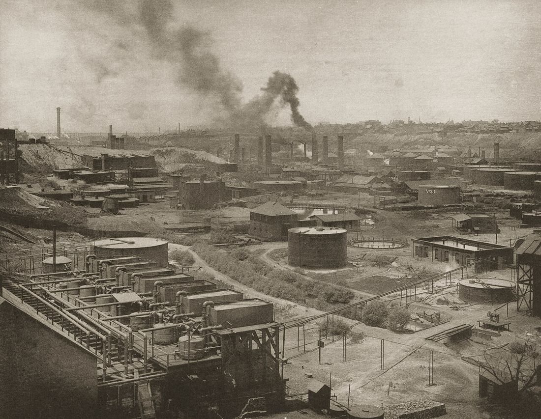 Oil refinery with tanks and smoking chimneys, old photograph