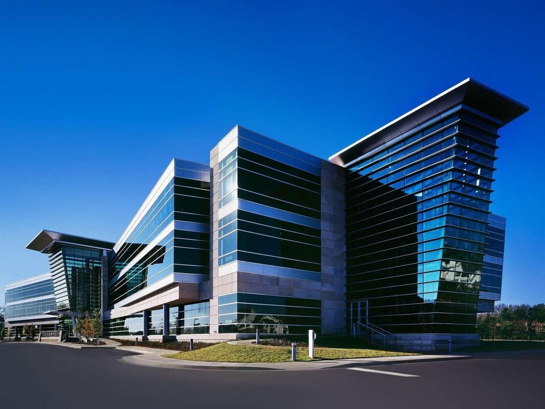 FedEx: Angular glass office building with layered metal bands and an overhanging roof under a deep blue sky