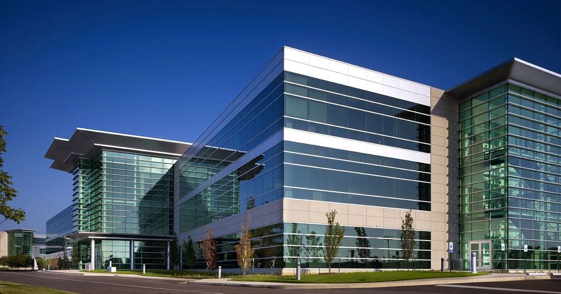 FedEx: Four-story glass office building with a projecting roof and young trees in front