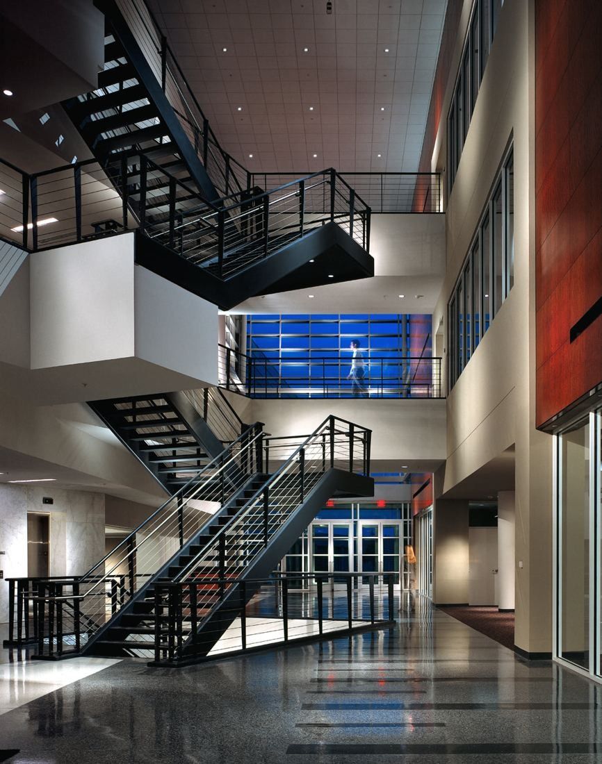 FedEx: Tall atrium with black steel stairs and bridges, polished terrazzo floor and a blue-lit glass wall