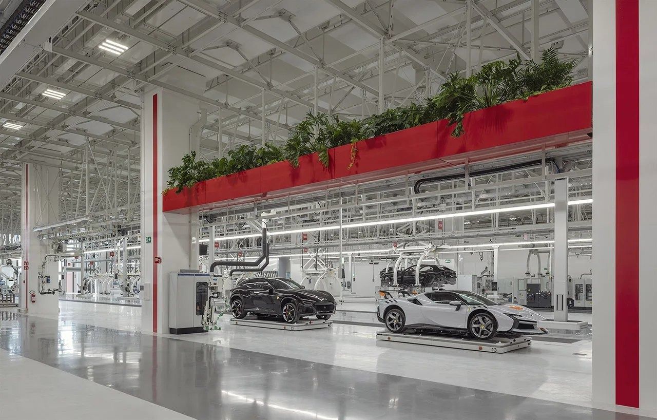 Bright assembly hall with cars on lines and a red planter beam