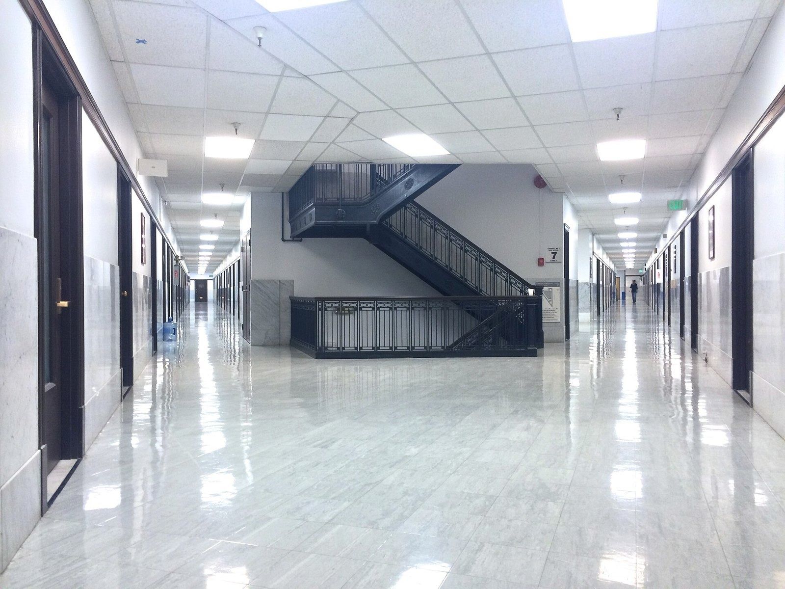 Figma: Glossy white corridor with office doors and a staircase in the middle
