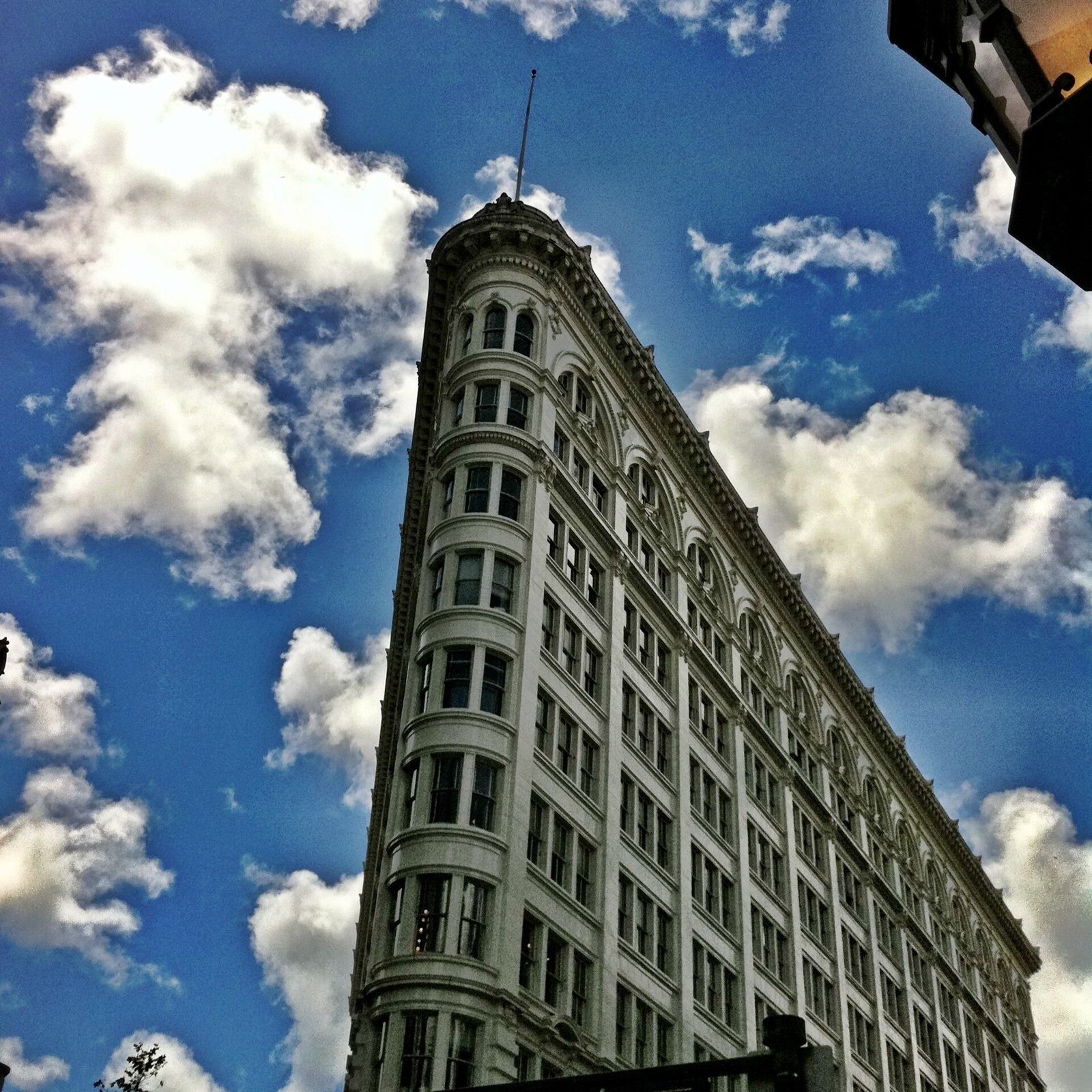 Figma: Looking up at the curved corner of the building against a blue sky with clouds