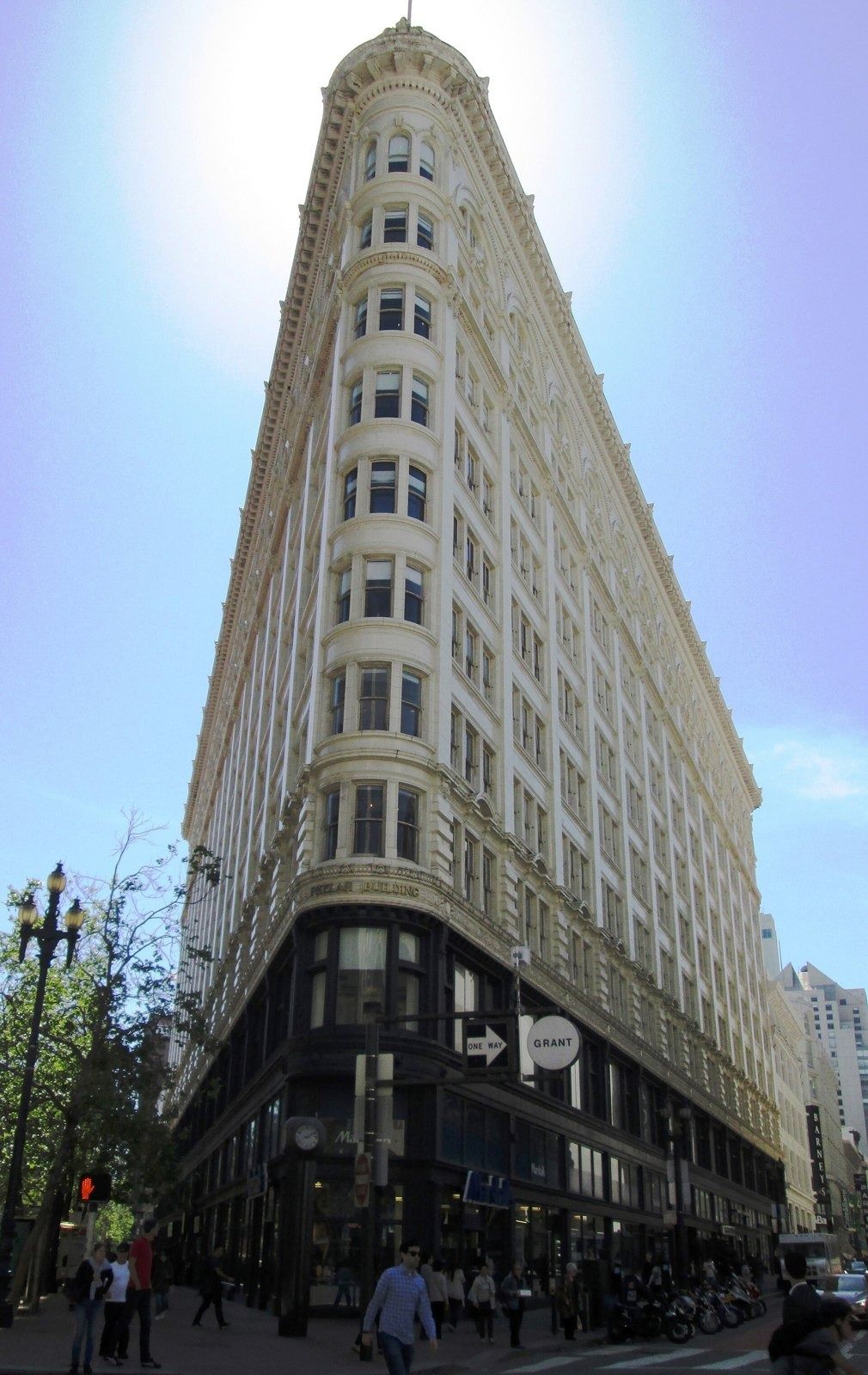 Figma: Narrow corner of a cream flatiron-shaped office building seen from street level