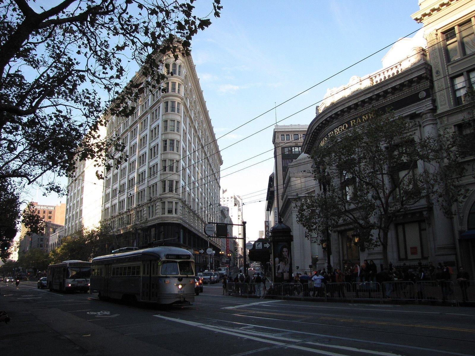 Figma: Tall cream flatiron-shaped building on a corner of Market Street with a vintage streetcar in front