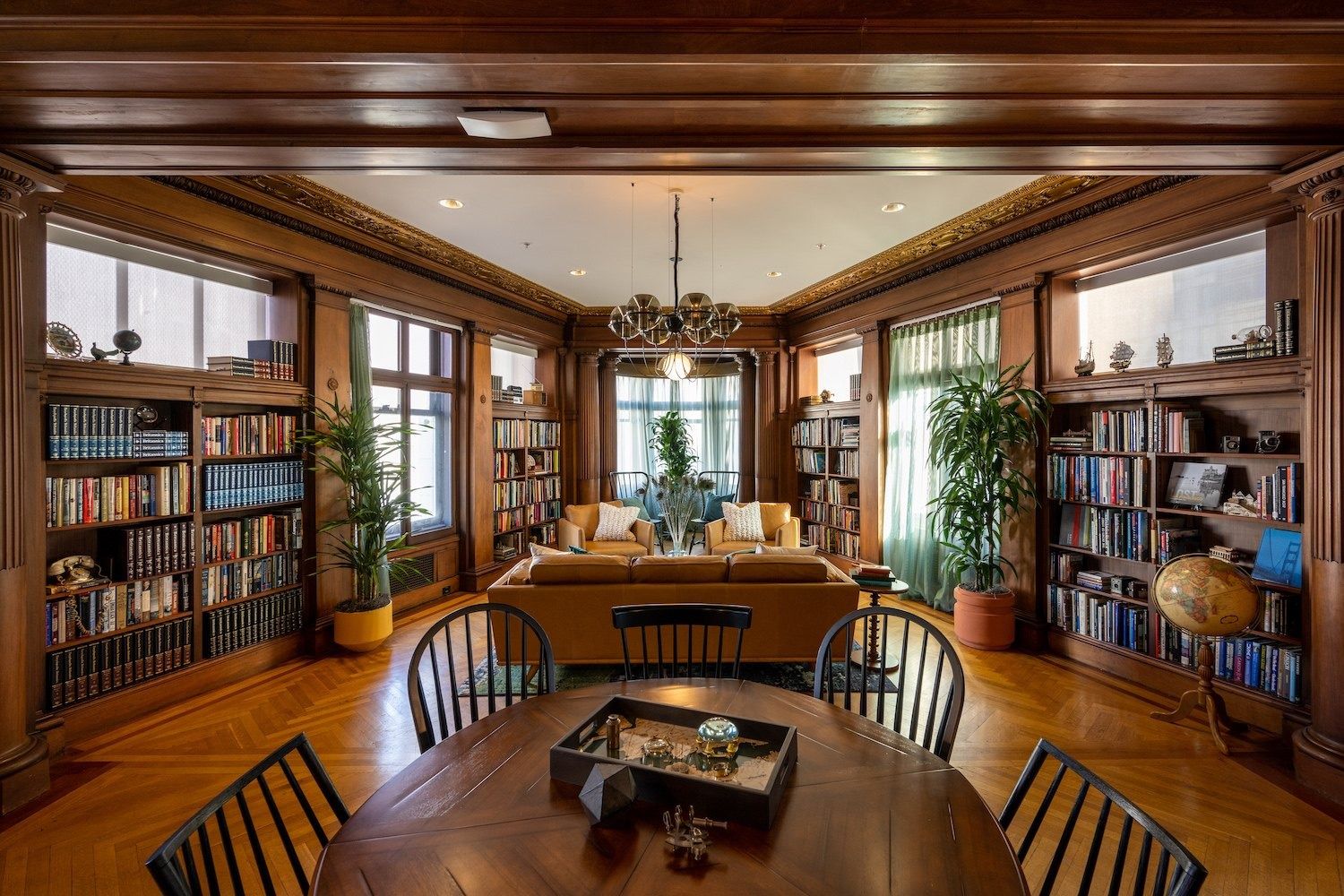 Figma: Wood-panelled library room with built-in bookshelves, a sofa and a round table