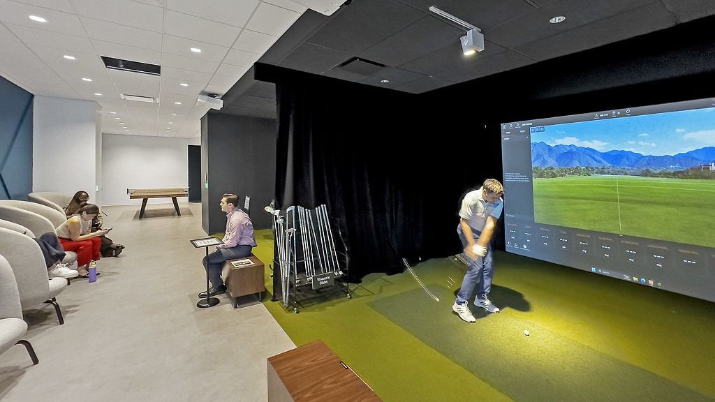 FIS: A room with a golf simulator screen next to lounge chairs and a pool table