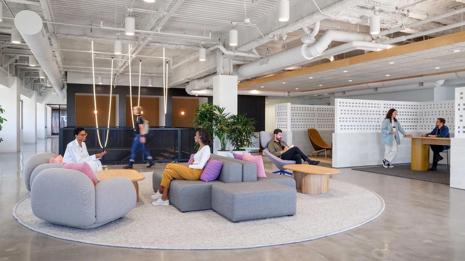 Fivetran: A round lounge with soft grey seats and purple cushions on a white rug