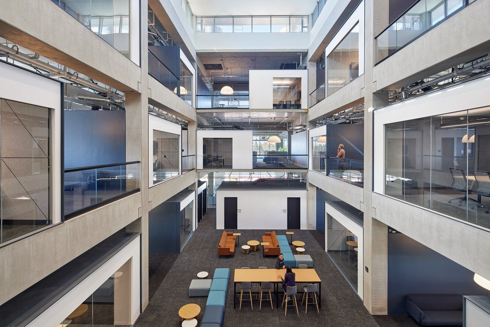 Fortinet: Atrium seen from above with concrete frame, glass-fronted rooms on each level and a lounge on the ground floor