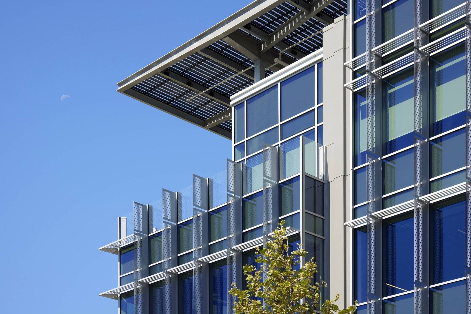 Fortinet: Close view of the building corner showing glass curtain wall, vertical fins and the projecting roof canopy