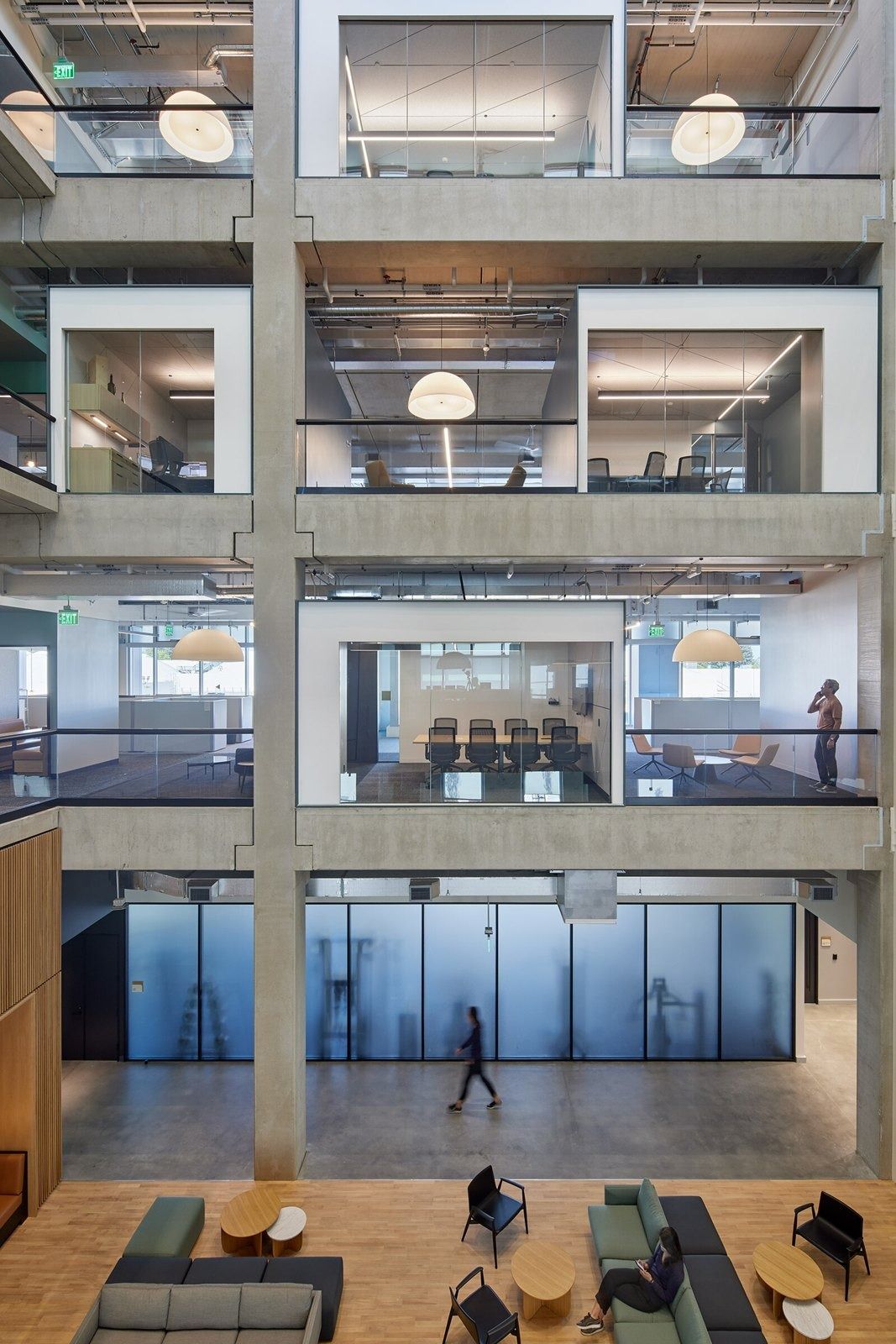 Fortinet: Concrete-framed atrium with stacked glass-walled rooms and seating on the ground floor