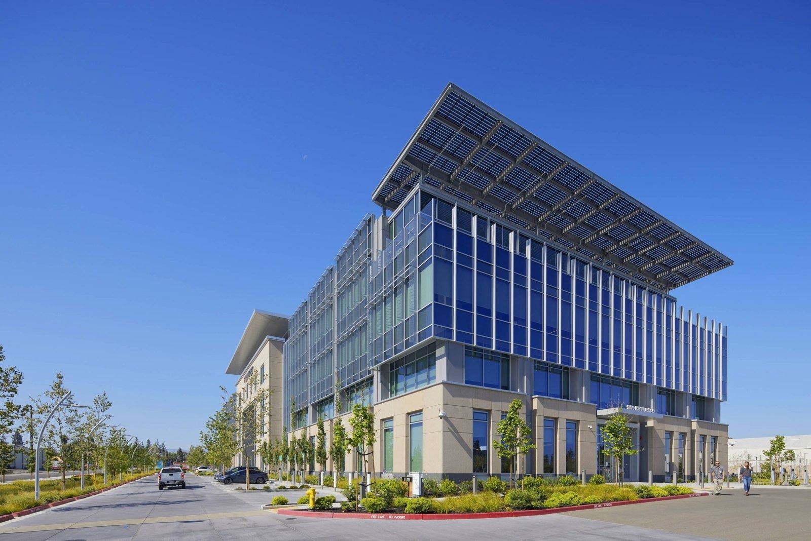 Fortinet: Corner view of the glass office wing with its roof canopy, seen from a landscaped driveway