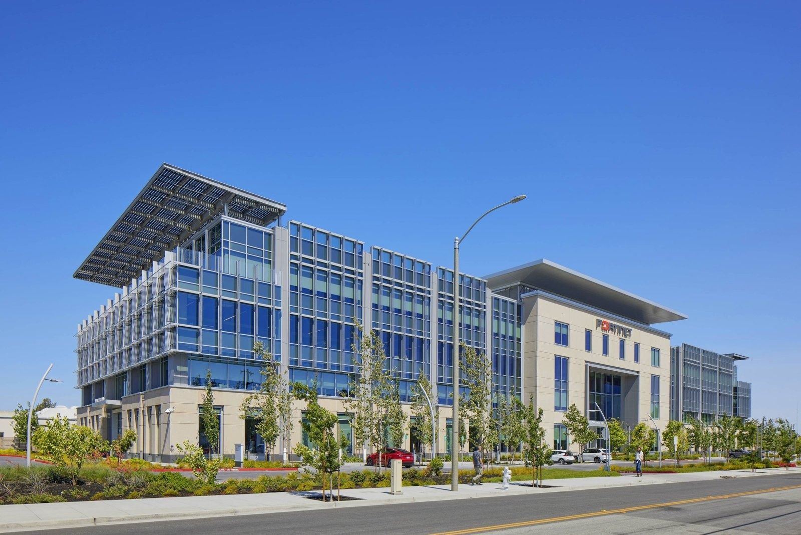 Fortinet: Long side of the building along a road, with a glass wing and the stone entrance block beyond