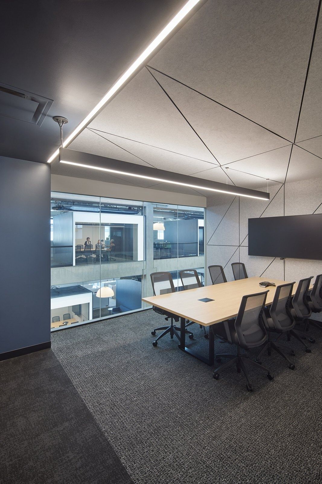 Fortinet: Meeting room with a long table, black chairs, a wall screen and angled linear ceiling lights