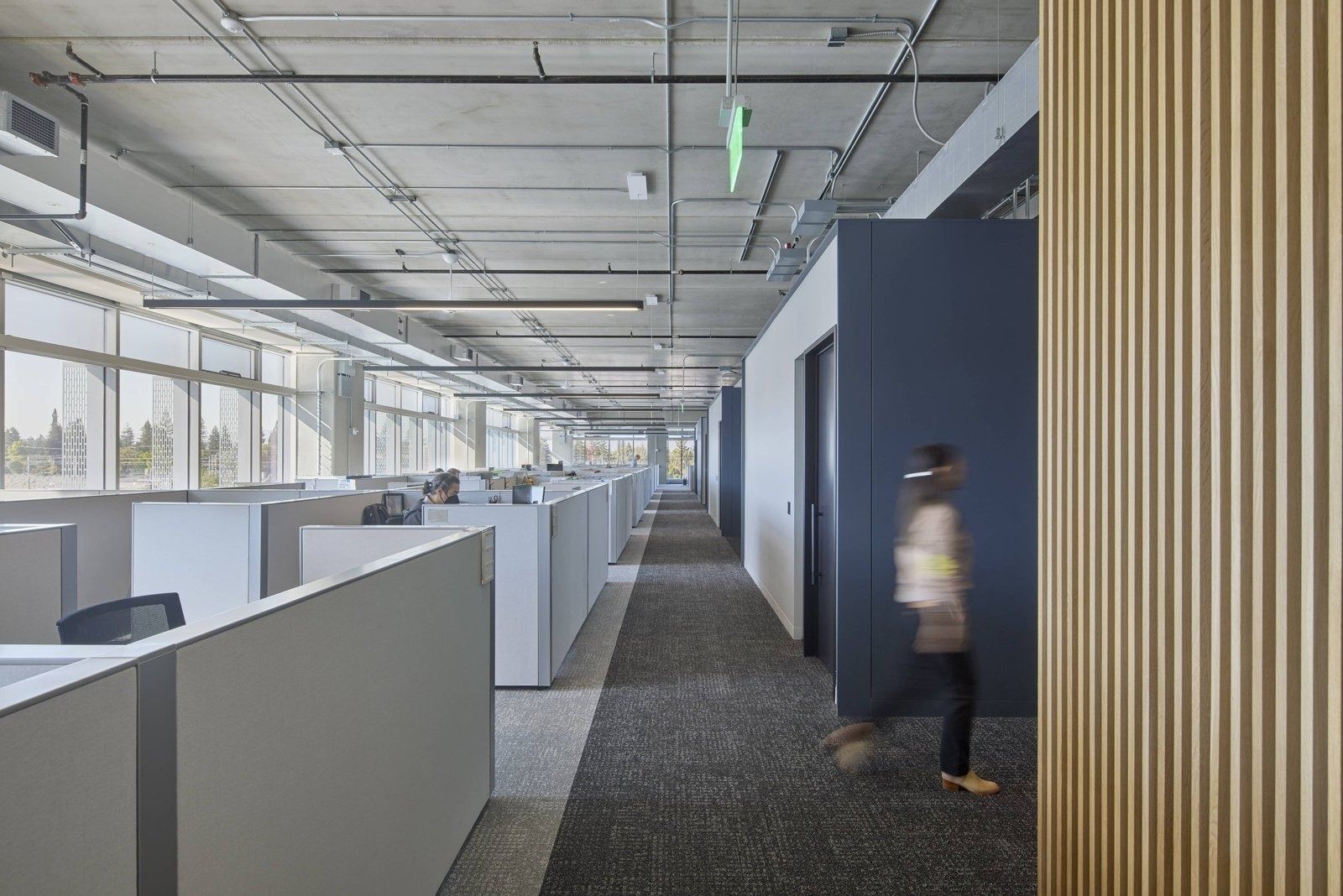 Fortinet: Open office floor with rows of grey workstations beside a wide aisle and wood slat panel