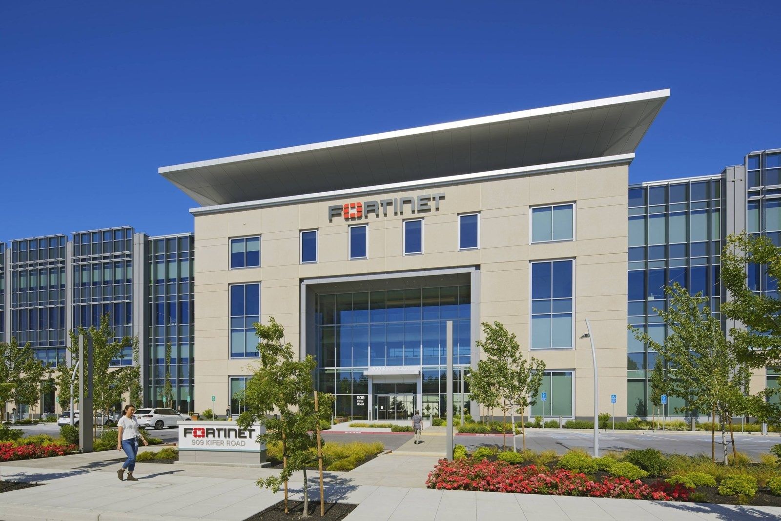 Fortinet: Stone-clad entrance block with a large glass entry and the company name on the facade, flanked by glass office wings