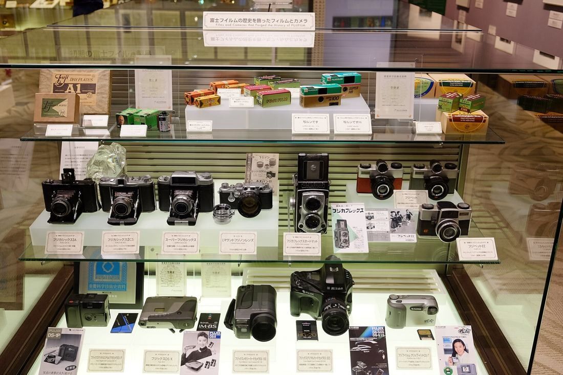 Fujifilm: Glass display case filled with vintage cameras and film boxes