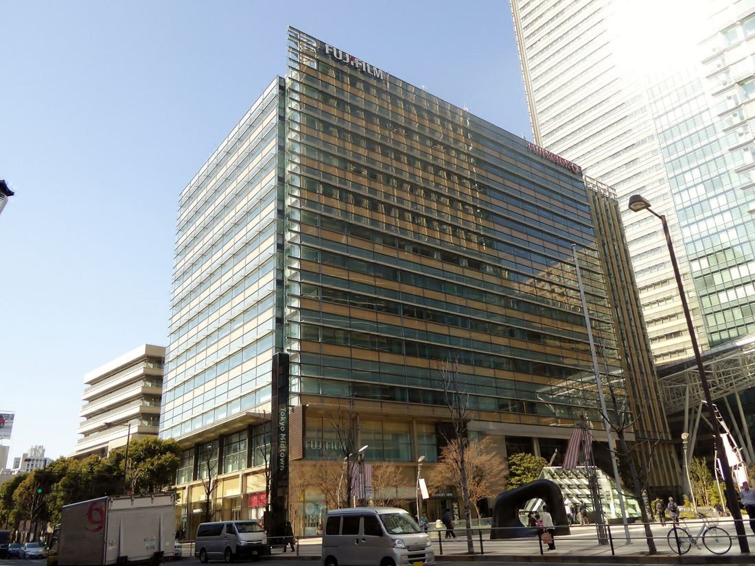 Fujifilm: Glass office building on a street corner with parked vans in front