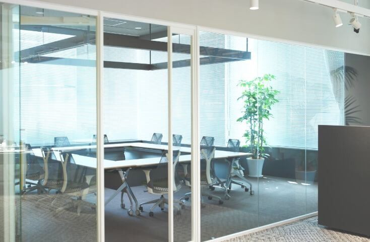 Fujifilm: Glass-walled meeting room with a long table and office chairs