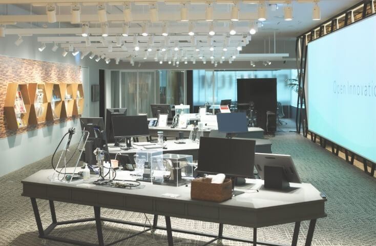 Fujifilm: Open office area with desks, monitors and a large bright wall screen