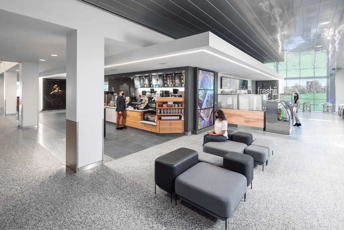 General Mills: Coffee counter and grab-and-go café behind upholstered benches on a terrazzo floor