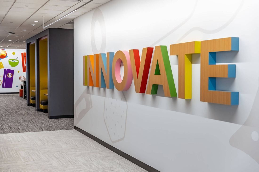 General Mills: Corridor with colorful three-dimensional lettering on a white wall and yellow-lined booths